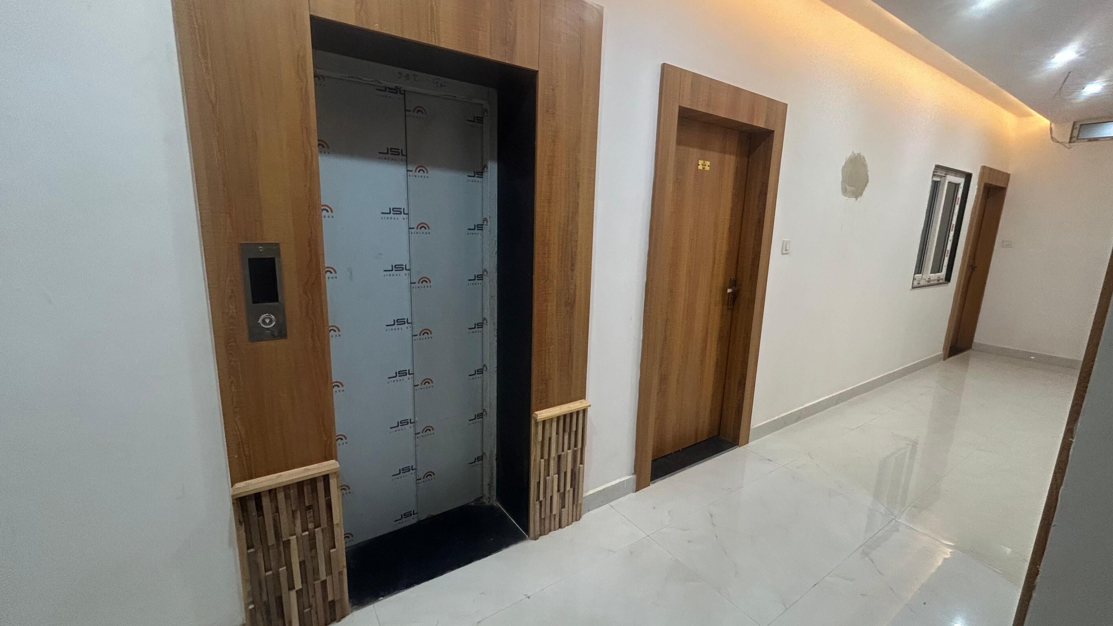 A hallway with two wooden doors, one with a security keypad, and a tiled floor.