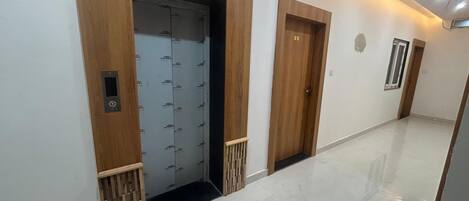 Un pasillo con dos puertas de madera, una con teclado de seguridad, y suelo de baldosas.