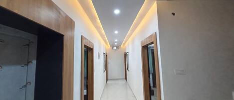 A hallway with wooden doors, recessed lighting, and a tiled floor.