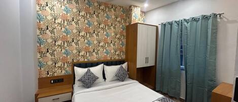 Un dormitorio con cama, armario, mesita de noche y cortina.