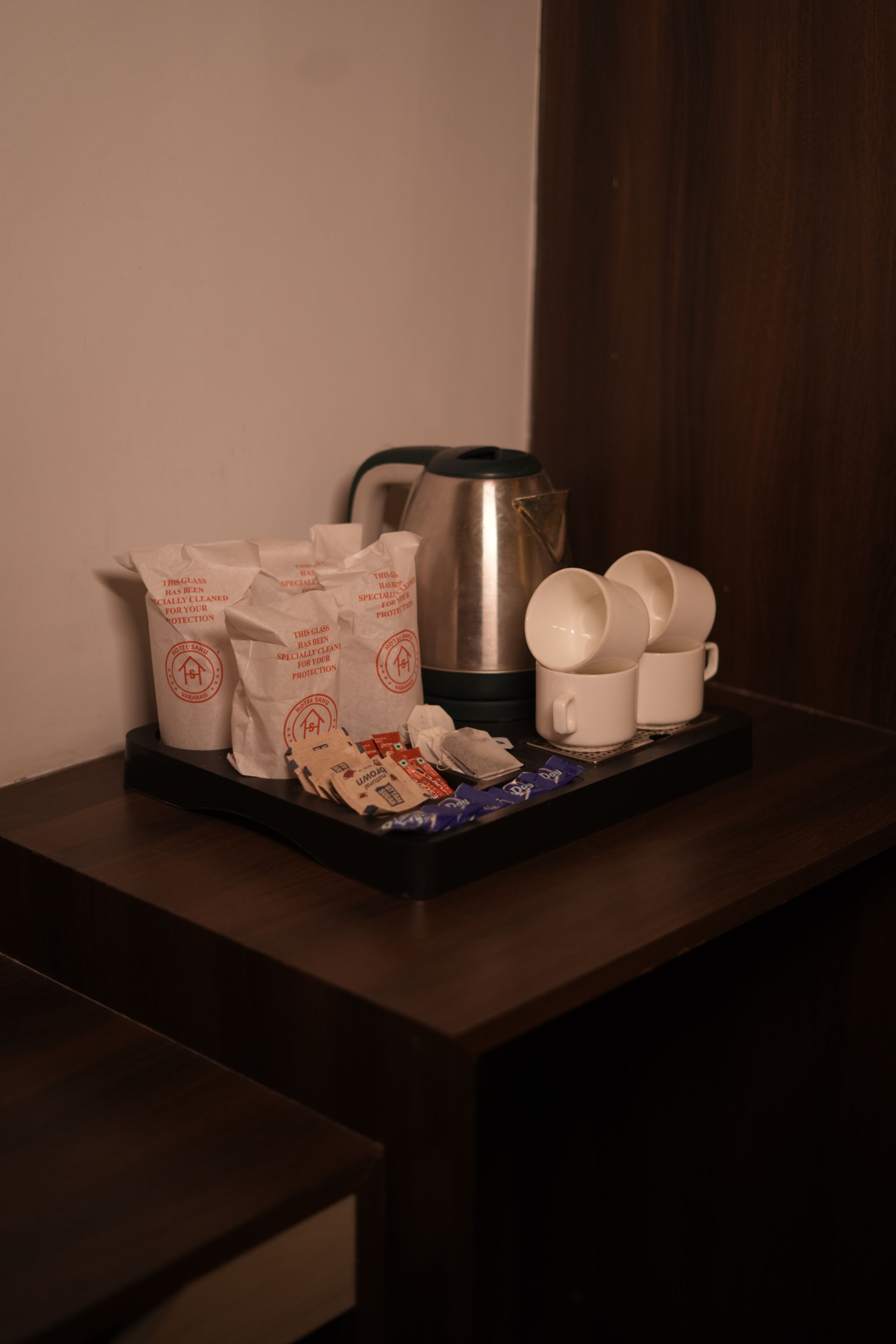 Una bandeja con tazas de café, una cafetera y bolsas de papel sobre una mesa de madera.