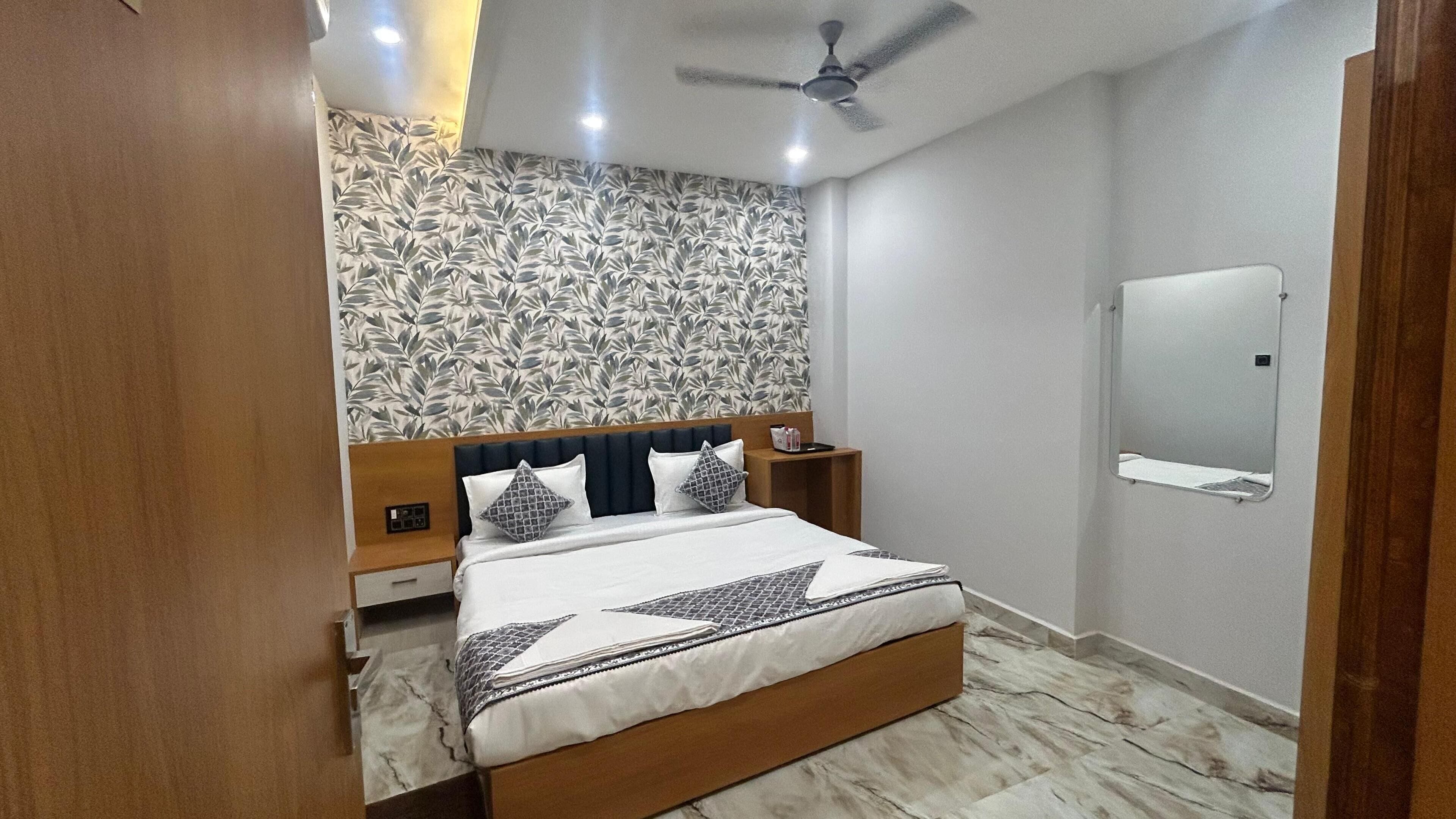 Une chambre à coucher comprenant un lit, des tables de chevet, un ventilateur de plafond, un miroir et un papier peint à motifs.