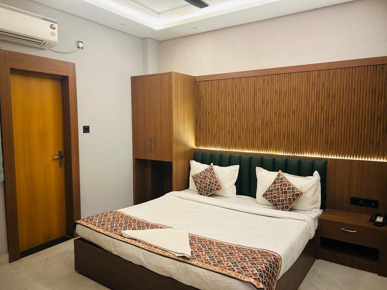 A hotel room with a large bed, wooden headboard, and a built-in wardrobe.