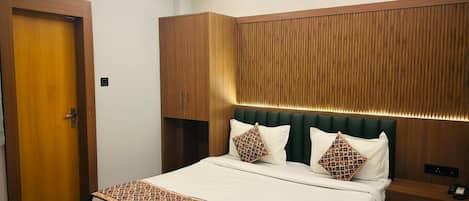 A hotel room with a large bed, wooden headboard, and a built-in wardrobe.