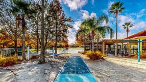 A boardwalk with a shuffleboard area, surrounded by trees and a covered seating area. - Spacious, 7R, 4.5BA Pool/Spa Home With Outside Covered Seating Area (166) (Kissimmee)