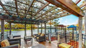A covered outdoor deck with wicker furniture and a view of a lake. - Spacious, 7R, 4.5BA Pool/Spa Home With Outside Covered Seating Area (166) (Kissimmee)