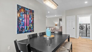 A dining area with a black table, blue vases, and a colorful abstract painting. - Perfect cottage - Refined Comfort Meets Pet-friendly Backyard Serenity (Tomball)