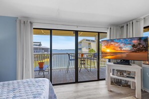 Habitació d'hotel amb balcó, un llit, una televisió i vistes a la platja.