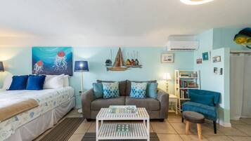 A cozy living room with a bed, a sofa, a coffee table, and a bookshelf.