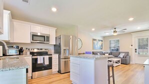 A modern kitchen with white cabinets, stainless steel appliances, and a central island. - Steps from the Sand - New 3BR Beach Cottage Near Keesler AFB & Gulf Fun (Biloxi)