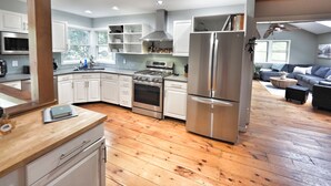 Une cuisine moderne avec des armoires blanches, des appareils en acier inoxydable et un plancher en bois.