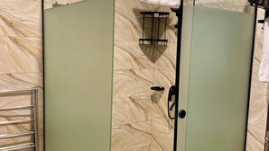 Une douche fermée par des parois de verre, dotée d’un porte-serviettes et d’une porte de douche en verre.