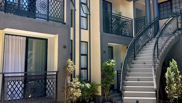 Un bâtiment moderne doté d’un escalier central, de nombreux balcons agrémentés de rampes décoratives et de plantes en pot.