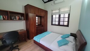 Une chambre à coucher comprenant un lit, un bureau, une armoire et une fenêtre avec des stores.