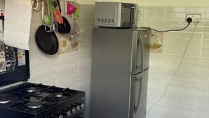 A kitchen with a gas stove, a microwave, and a refrigerator. - Cozy 1BR Near Two Rivers & UN | Fast Wi-Fi (Nairobi)