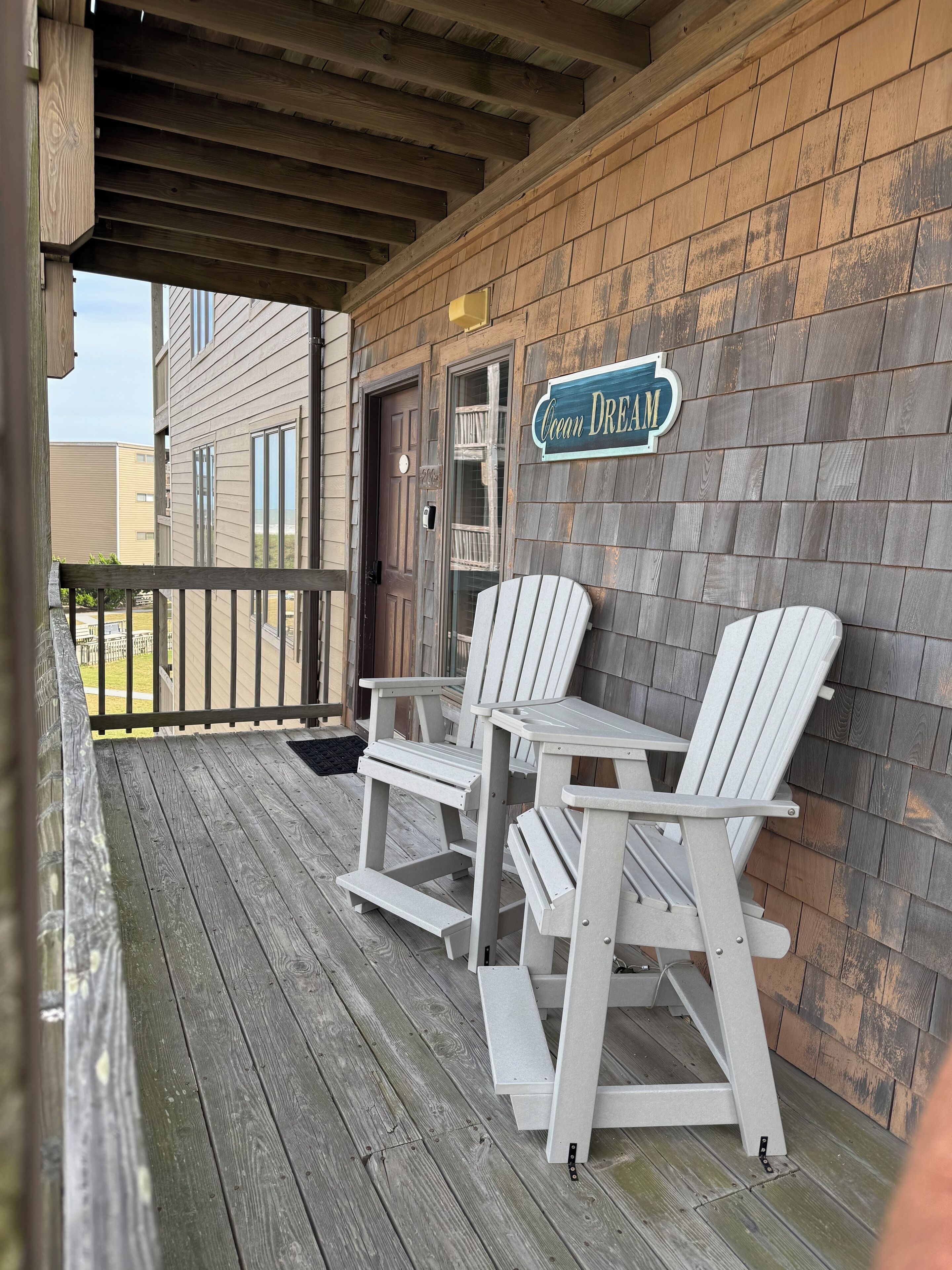 A wooden deck with Adirondack chairs and a sign that reads "Ocean Dream."