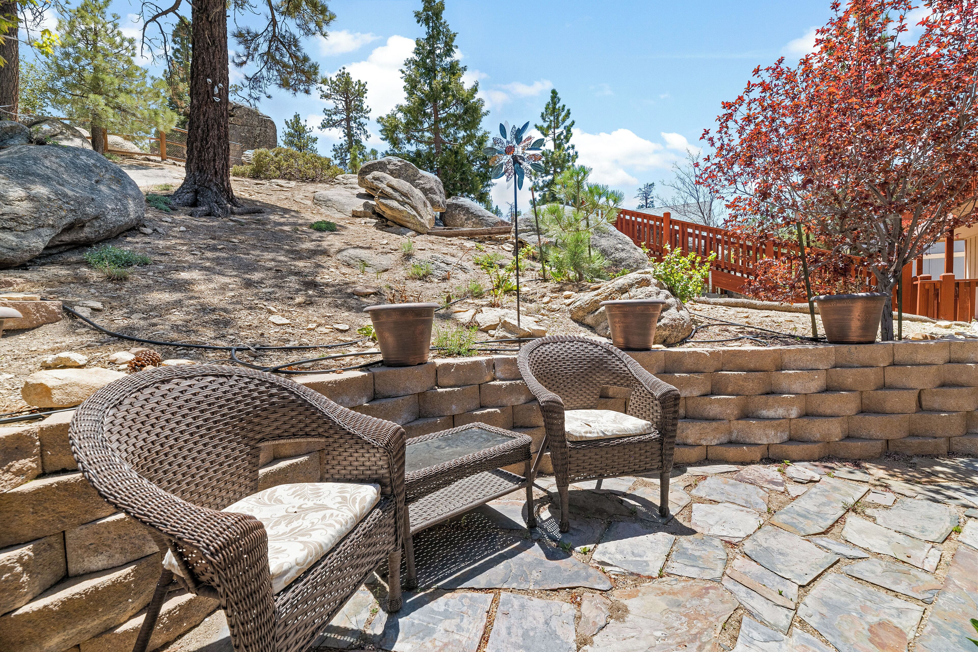 A patio area with wicker furniture and stone flooring.
