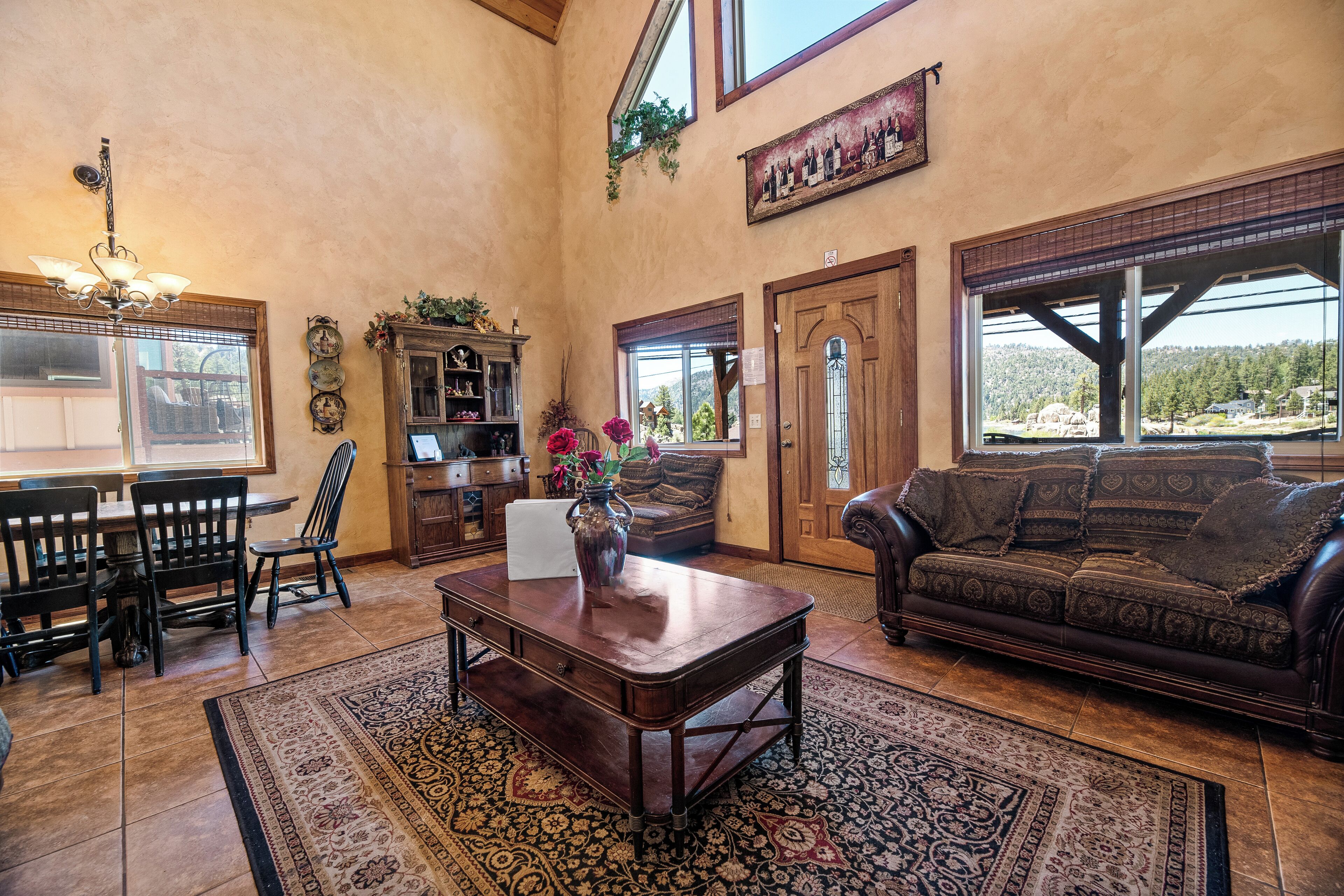 A spacious living room with a dining area, a large window with a view, and a chandelier.