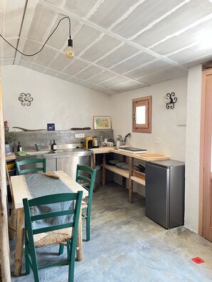 Eine kompakte Küche mit Essbereich, ausgestattet mit Spüle, Herd, Kühlschrank und einem Fenster.