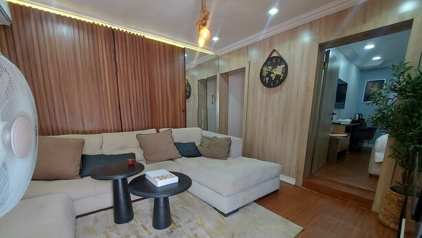 A modern living room with a beige sofa, a small round table, and a fan.