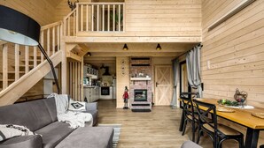 Interior acollidor d'una cabana amb sala d'estar, menjador i cuina.
