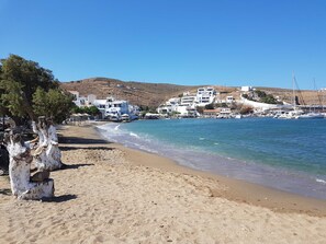 A beach with white buildings, a tree, and boats in the water. - Theis Seafront Retreat - Loutra Seaview Bliss (Kithnos)