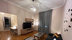 Una sala de estar moderna con un sofá, una mesa de centro, un televisor y una zona de comedor con una mesa y sillas.
