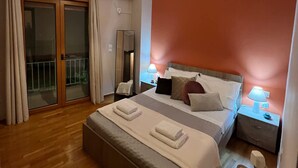 Un dormitorio con una cama grande, un ventilador de techo, una mesita de noche con lámpara, una puerta corrediza de vidrio y vistas al exterior.