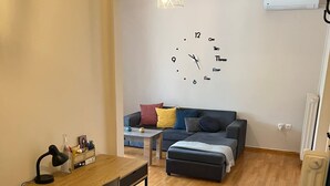 Un espacio habitable compacto con piso de madera, un sofá, una mesita y un escritorio con una silla.