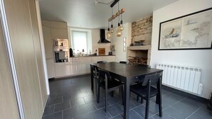 A modern kitchen with a dark tiled floor, a central island, and pendant lighting. - Pink Granite Coast in Brittany: Comfortable Home with Wi-Fi (Trébeurden)