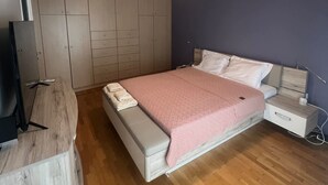 A bedroom with a bed, bedside tables, a wardrobe, and a ceiling light. - Sunny Coastal Escape in Alimos (Alimos)