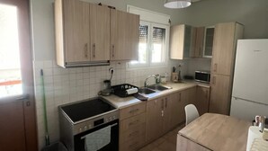 A compact kitchen with a stove, oven, sink, and a small dining table. - Sunny Coastal Escape in Alimos (Alimos)