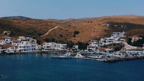 A coastal town with white buildings, a marina with boats, and a hilly backdrop. - Alos Seafront Gem - Loutra Seaview Escape (Kithnos)