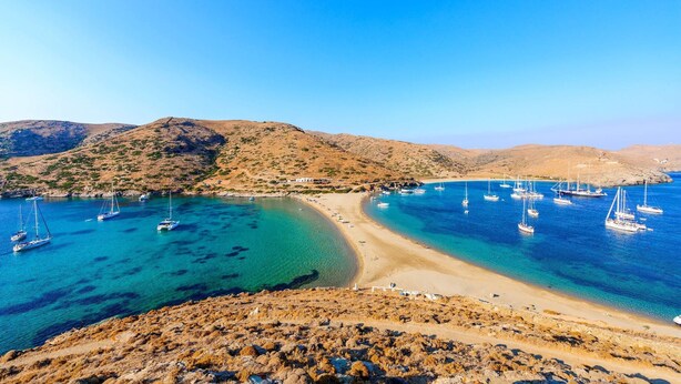 A coastal landscape with clear turquoise waters, a sandy beach, and rocky hills in the background. - Alos Seafront Gem - Loutra Seaview Escape (Kithnos)
