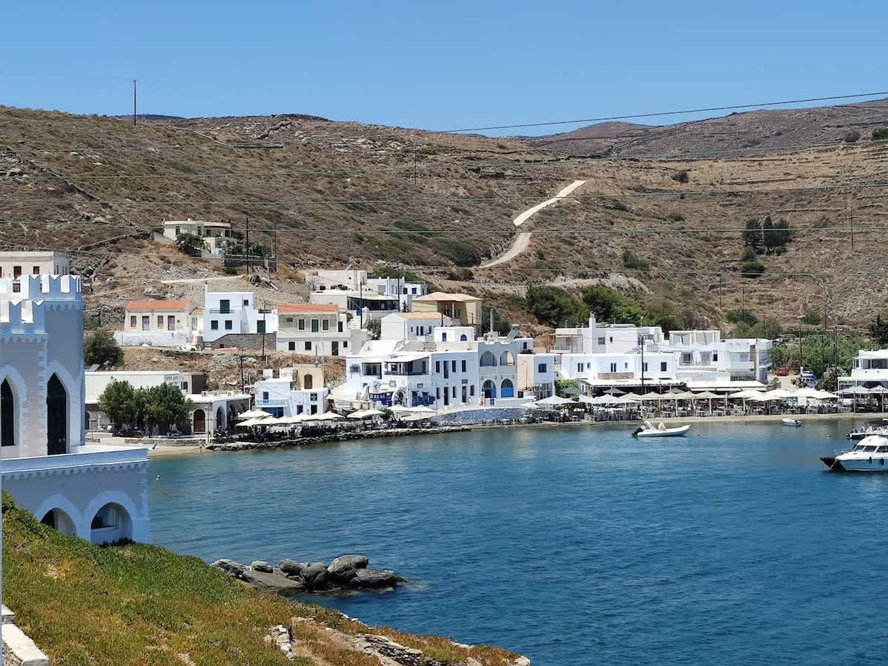 A coastal town with white buildings, a church, and a marina with boats.