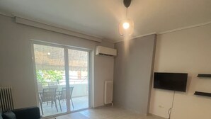 A modern living room with a sofa, coffee table, and TV. - Neos Kosmos Cozy Retreat - Cental Comfort (Athens)