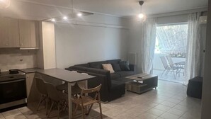 A modern living room with a dining area, a sofa, and a kitchen with a stove. - Neos Kosmos Cozy Retreat - Cental Comfort (Athens)
