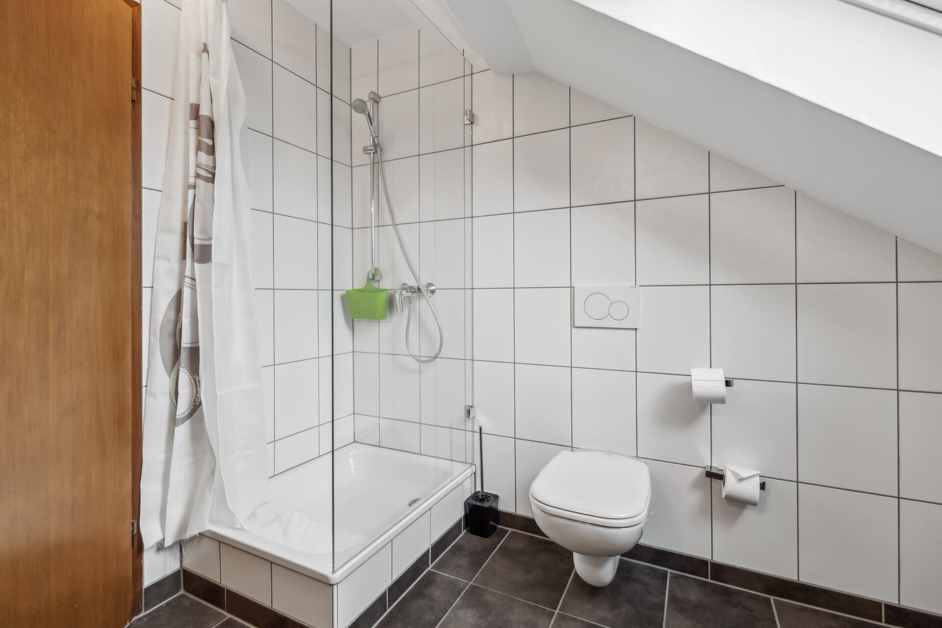 Un baño moderno con paredes de azulejos blancos, ducha, inodoro y bañera.