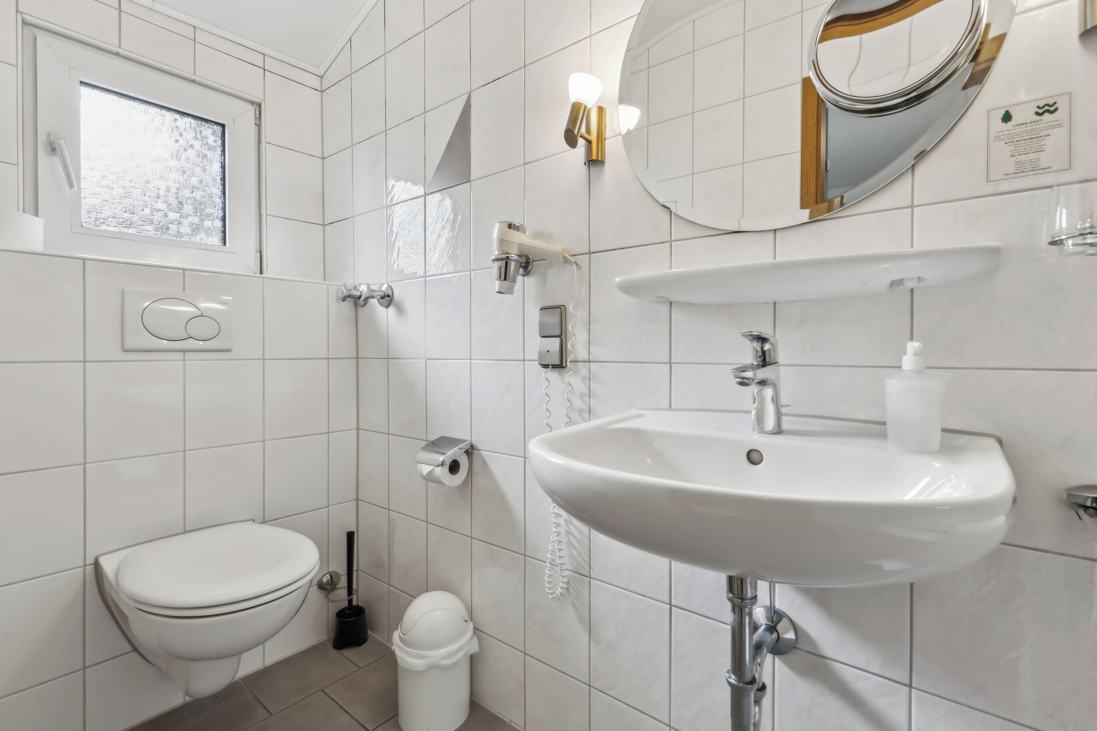 Un baño moderno con inodoro, lavabo y espejo.