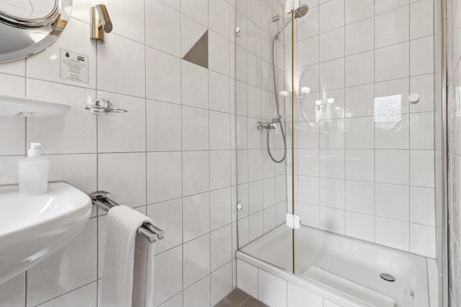 Ein modernes Badezimmer mit einer Duschkabine, einem weißen Waschbecken und einem Handtuchhalter.