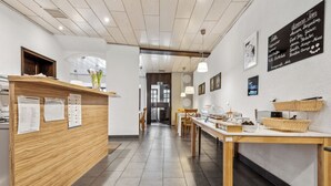 A modern cafe interior with a wooden reception desk, a menu board, and a counter with food items. - Hotel zum Erwin (Karlsruhe)