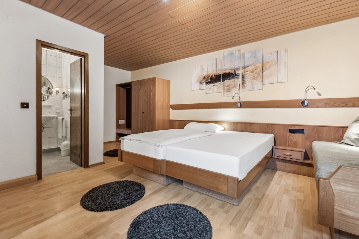 A modern bedroom with a wooden headboard, a double bed, a bedside table, and a nightstand.