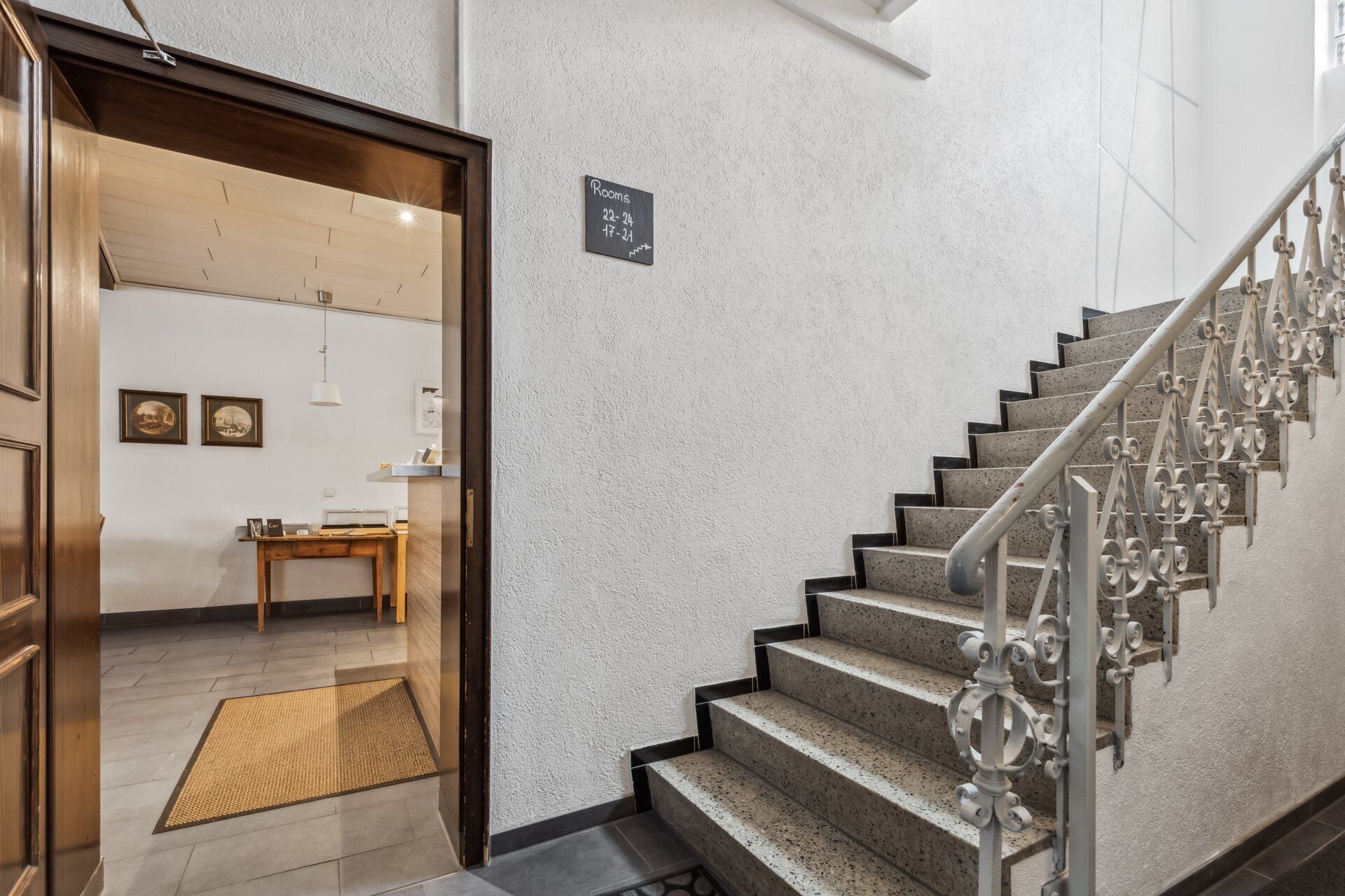 A staircase with a metal handrail and a sign indicating room availability.