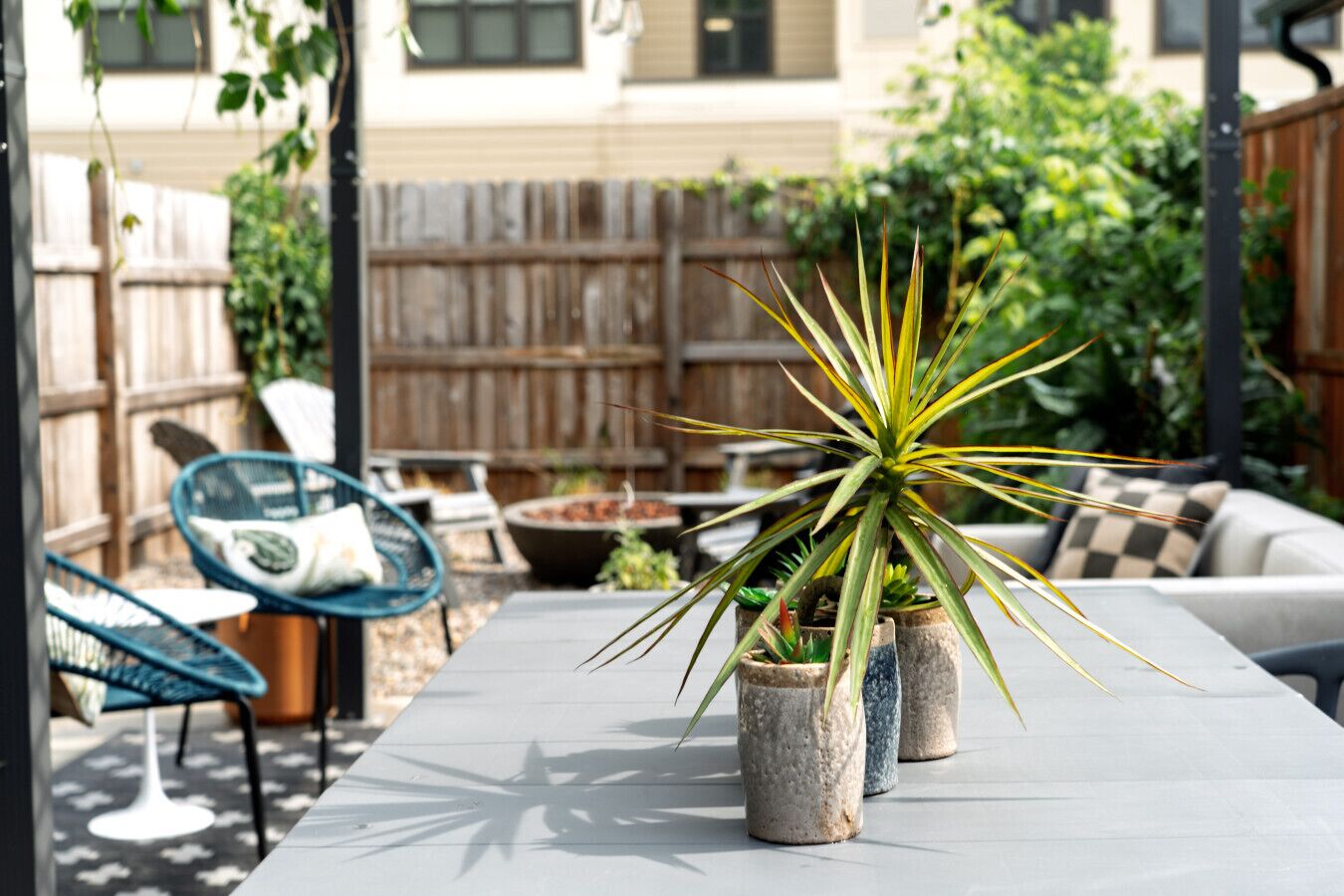 En terrasse med et bord, stole og plantekrukker.