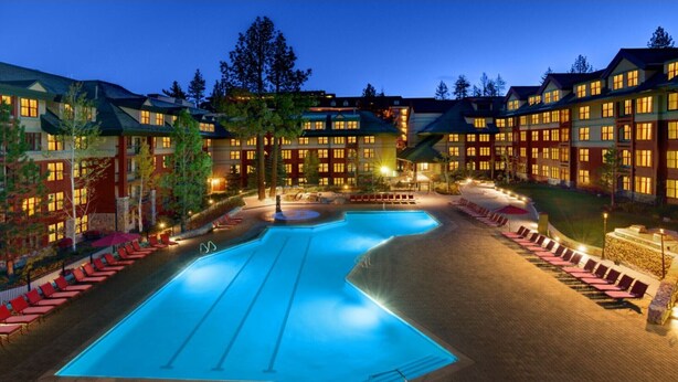 A hotel with a large swimming pool, multiple guest rooms, and outdoor seating areas.