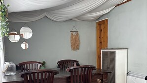 A dining area with a table and chairs, a hanging mirror, and a wall-mounted decorative piece. - Camping 2000 - Glamourtent (Osecná)
