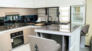 Una cocina moderna con salpicadero de mármol, electrodomésticos de acero inoxidable y una isla grande con taburetes de bar.
