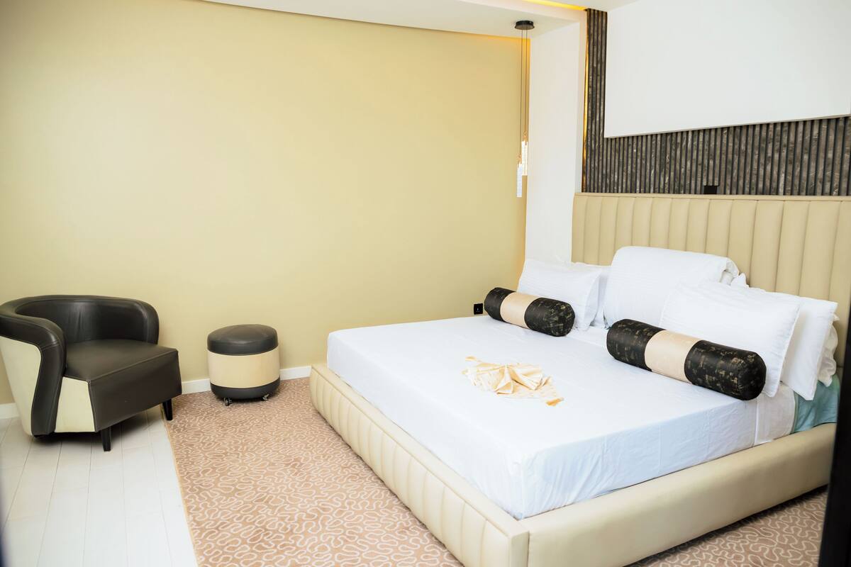 Ein Hotelzimmer mit einem Bett, einem Sessel und einem kleinen Hocker.