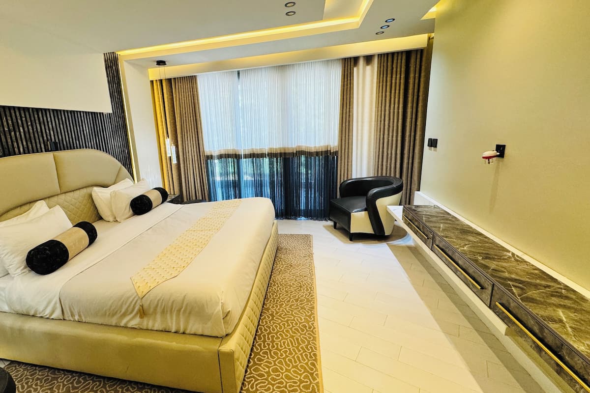 Ein modernes Hotelzimmer mit einem großen Bett, einer Sitzecke und Blick ins Freie.