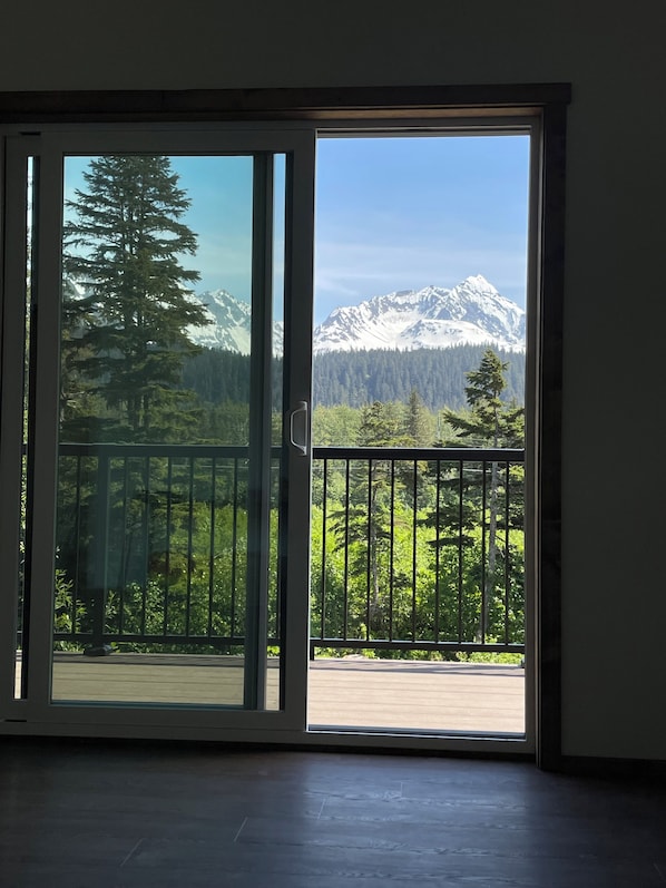 Une pièce dotée d’une porte-fenêtre coulissante donnant sur un balcon avec vue sur les montagnes.